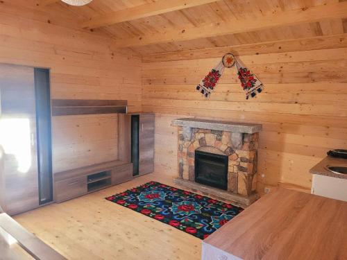 a room with a fireplace in a log cabin at Cabanuta Din Deal in Racoviţa