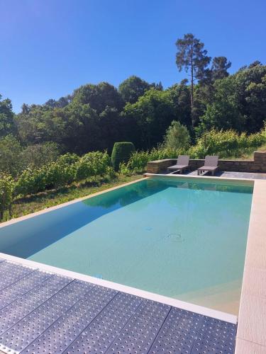 a large swimming pool with two chairs and trees at Quinta de Santa Júlia in Peso da Régua