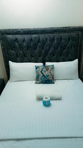 1 cama blanca grande con cabecero negro y almohadas en Vee Apartment, en Mombasa