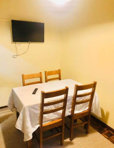 a table with three chairs and a television on a wall at Cantinho da Glória in Aveiro