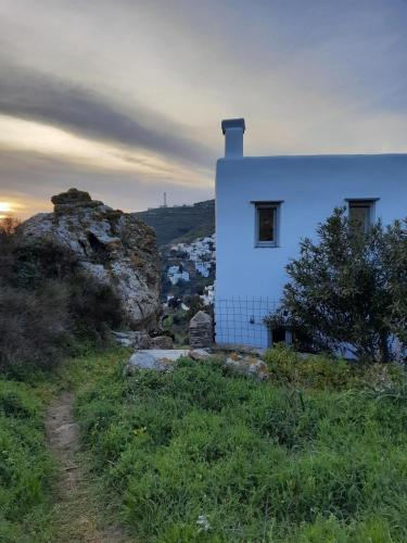 a white house on a hill next to a rock at By The Stone Tinos in Triandáros