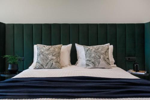 a large bed with a green headboard and pillows at Side by Side Suites in Athens Riviera by The Olon in Athens