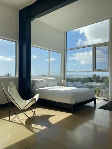 a bedroom with a bed and a chair and windows at Abpopa Hillcrest in San Diego