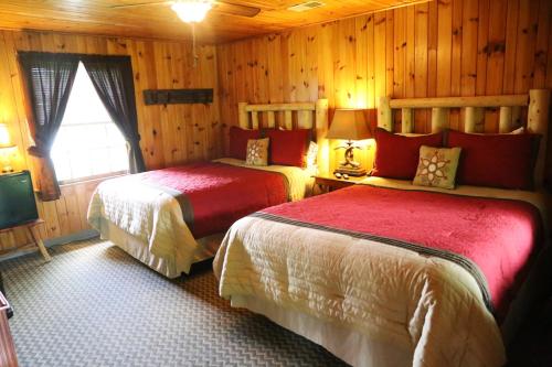 two beds in a room with wooden walls and a tv at Grandview Lodge in Waynesville