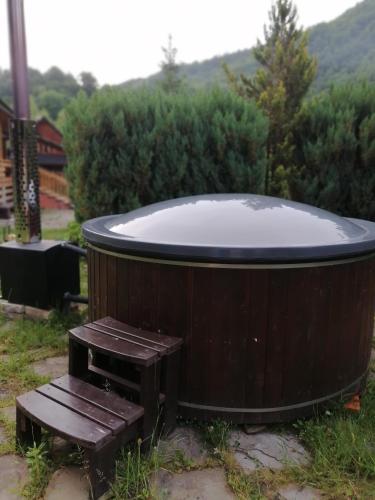 a wooden hot tub with a bench in a yard at Stara Khata Карпати in Sheshory
