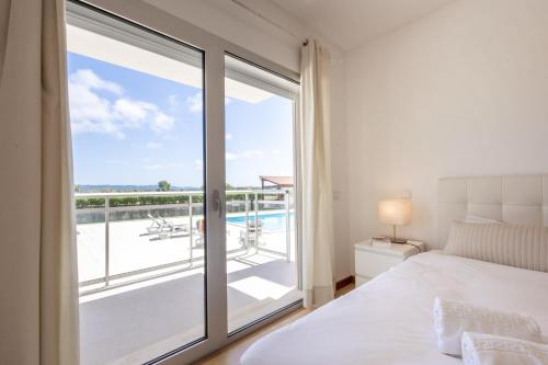 um quarto com uma cama e uma varanda com vista em Carmona A T2 - By Smarthomes em São Martinho do Porto