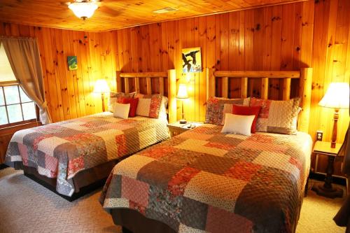 two beds in a room with wood paneled walls at Grandview Lodge in Waynesville