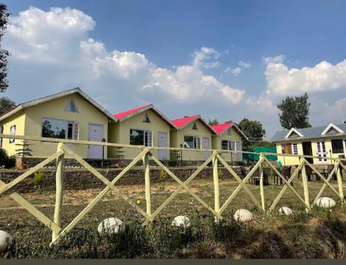 a fence in front of a house with houses at THE HIDEAWAY Homestay Chail in Chail