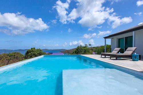 a swimming pool with two lounge chairs next to a house at Tropical Panorama in Cruz Bay