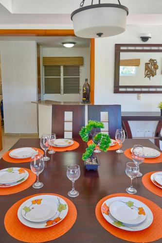 a dining room table with plates and glasses on it at Comfy Spacious Villa W- Pool, Jacuzzi, Bbq in Juan Dolio