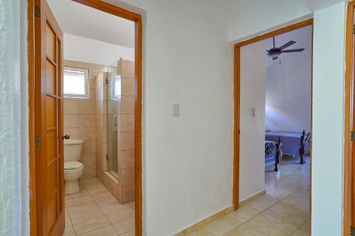 a bathroom with a toilet and a door to a room at Comfy Spacious Villa W- Pool, Jacuzzi, Bbq in Juan Dolio
