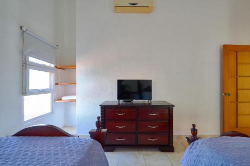 a bedroom with a dresser with a television on it at Comfy Spacious Villa W- Pool, Jacuzzi, Bbq in Juan Dolio