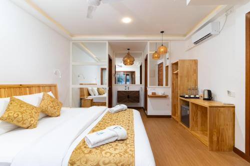 a bedroom with a large white bed and a kitchen at Ostrov Palm in Ukulhas