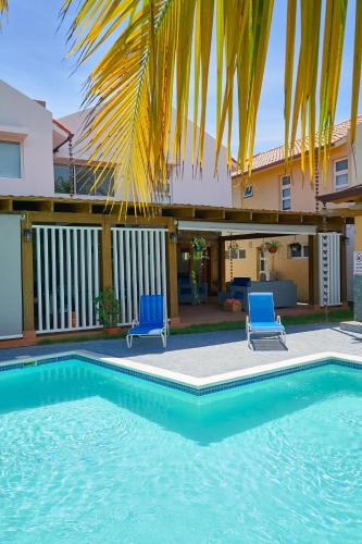 a swimming pool with two blue chairs and a house at Comfy Spacious Villa W- Pool, Jacuzzi, Bbq in Juan Dolio
