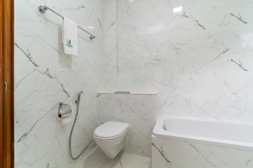 a white bathroom with a toilet and a sink at Ostrov Palm in Ukulhas