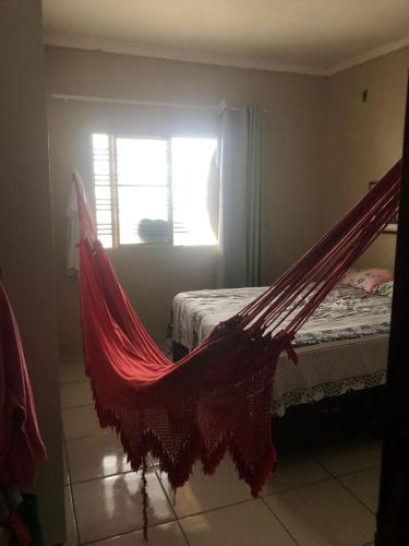 eine Hängematte in einem Zimmer mit einem Bett und einem Fenster in der Unterkunft Casa da Mari in Petrolina