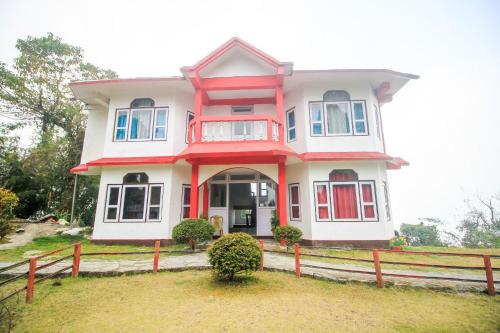 a red and white house with a wooden fence at Hotel O Uzen Homestay in Lachung