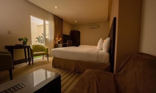 a hotel room with a bed and a desk at Rincon del Valle Hotel & Suites in San José