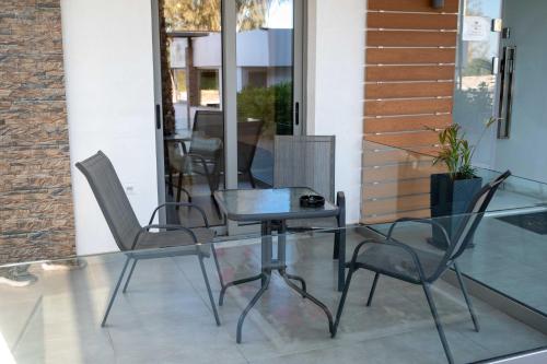 a glass table and chairs on a patio at Finikas Suites & Apartments Airport By Airstay in Artemida