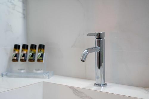 a bathroom sink with a faucet and three bottles of beer at Finikas Suites & Apartments Airport By Airstay in Artemida