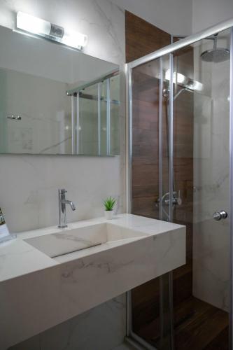 a white bathroom with a sink and a shower at Finikas Suites & Apartments Airport By Airstay in Artemida