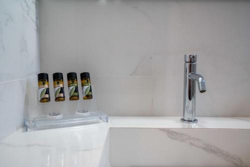 a bathroom with a faucet and three bottles of alcohol at Finikas Suites & Apartments Airport By Airstay in Artemida