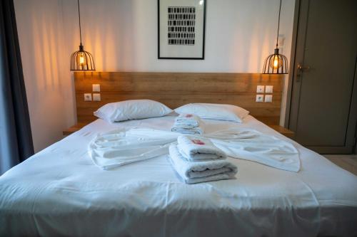 a white bed with towels on top of it at Finikas Suites & Apartments Airport By Airstay in Artemida