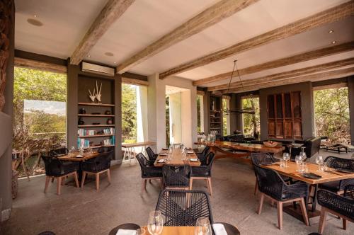 a restaurant with wooden tables and chairs and windows at Kapama Karula in Kapama Private Game Reserve