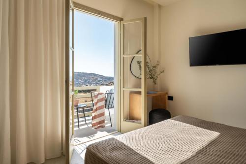 a bedroom with a bed and a window with a balcony at Philosophy of Mykonos Boutique Hotel in Mýkonos City