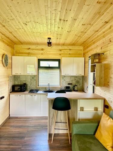 a kitchen with white cabinets and a green stool at M&M House Kazbegi in Stepantsminda