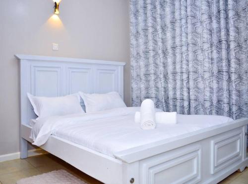 Una cama blanca con una vela encima en un dormitorio. en Mels Cosy Homes, en Nairobi