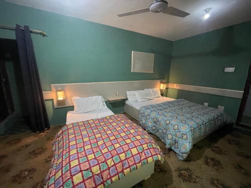 two beds in a room with green walls at Skardu Lodge in Skardu