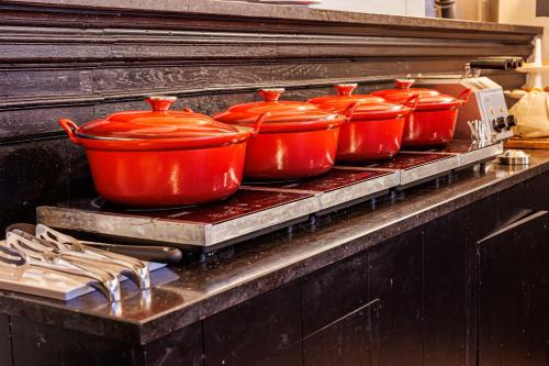 a row of red pots sitting on a stove at Grand Hotel Alkmaar in Alkmaar