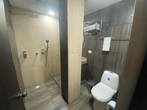 a bathroom with a white toilet and a shower at Hotel deluxe oasis de la colina boutique in Girardot