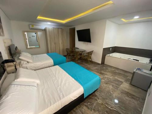 a hotel room with two beds and a table at Hotel deluxe oasis de la colina boutique in Girardot