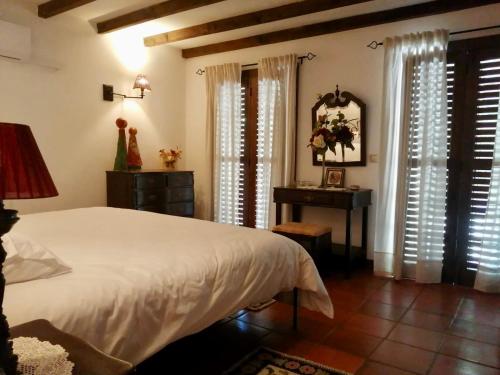 a bedroom with a bed and a table and windows at Moinho do Granjão - Water Mill in Mesão Frio