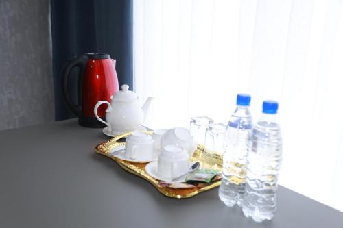 - un plateau avec des tasses et des bouteilles d'eau sur un comptoir dans l'établissement Hotel Shirin, à Isfara