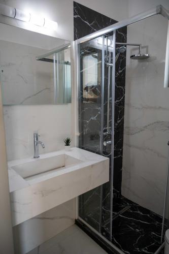a bathroom with a sink and a glass shower at Finikas Suites & Apartments Airport By Airstay in Artemida
