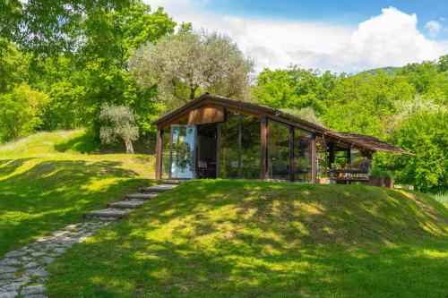 a glass house on a grassy hill with trees at Premignaga Natural Home in Gardone Riviera