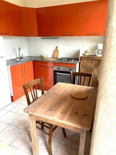 une table et des chaises en bois dans une cuisine avec des armoires orange dans l'établissement Armor, à Lannion