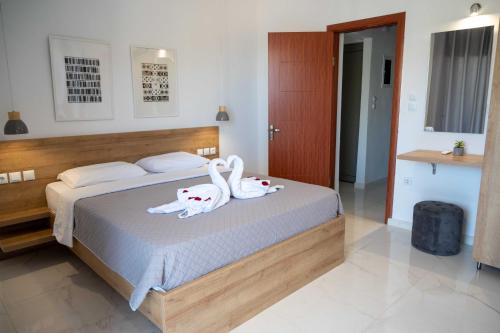two swans are sitting on a bed in a bedroom at Finikas Suites & Apartments Airport By Airstay in Artemida