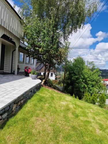 a house with a stone retaining wall and a yard at Eidsvåg in Bergen