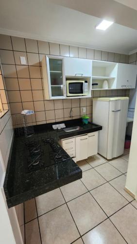 a kitchen with white cabinets and a black counter top at diRoma Fiori - Apartamentos JN in Caldas Novas