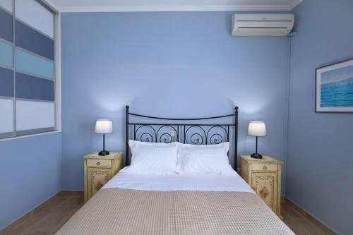a blue bedroom with a bed and two night stands at Amaryllis House Lefkada in Lefkada Town