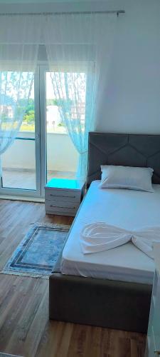 a bedroom with a bed and a large window at Sabi Apartment Golem Qerret in Golem