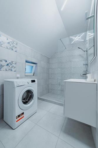 a white bathroom with a washing machine and a sink at Villa Russo in Râşnov