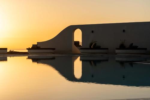 a pool of water with the sunset in the background at Philosophy of Mykonos Boutique Hotel in Mýkonos City
