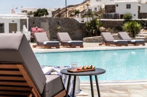 a table with a plate of fruit on it next to a pool at Philosophy of Mykonos Boutique Hotel in Mýkonos City