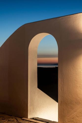 a view of the ocean through an arch in a building at Philosophy of Mykonos Boutique Hotel in Mýkonos City