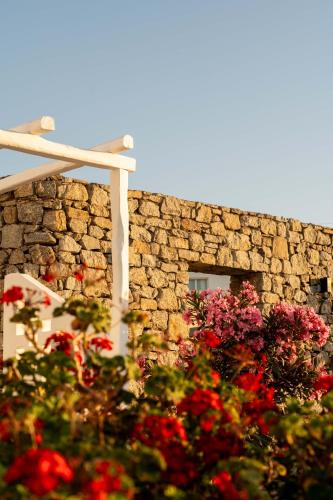 a stone building with flowers in front of it at Philosophy of Mykonos Boutique Hotel in Mýkonos City
